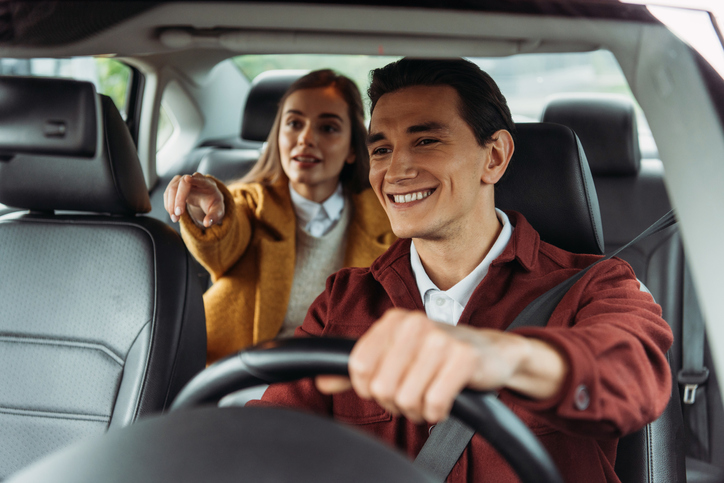 Smiling taxi driver with woman passenger pointing on road Smiling taxi driver with woman passenger pointing on road